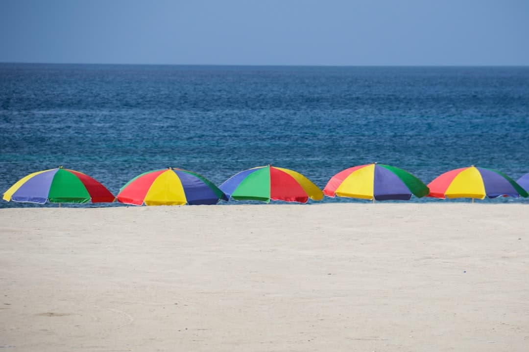 Kolorowe parasole na piaszczystej plaży nad morzem.
