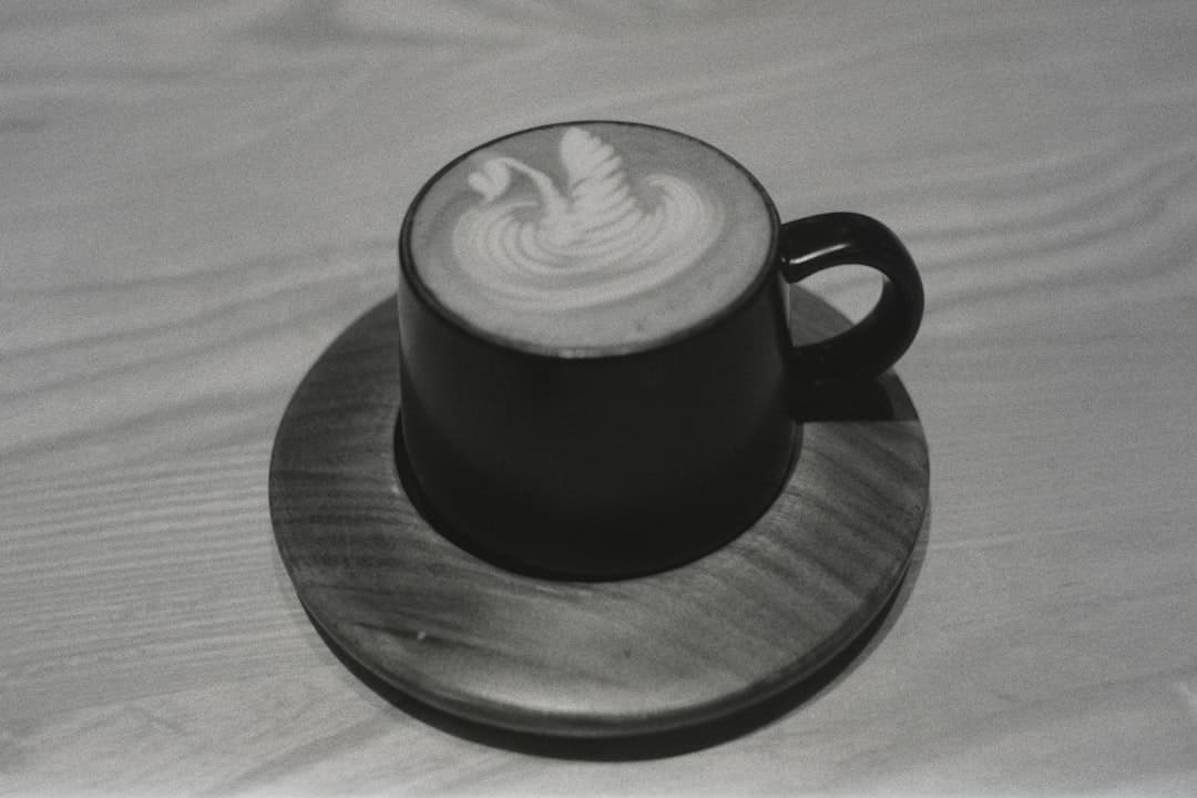 Filiżanka kawy latte z łabędziem na drewnianej podstawce.