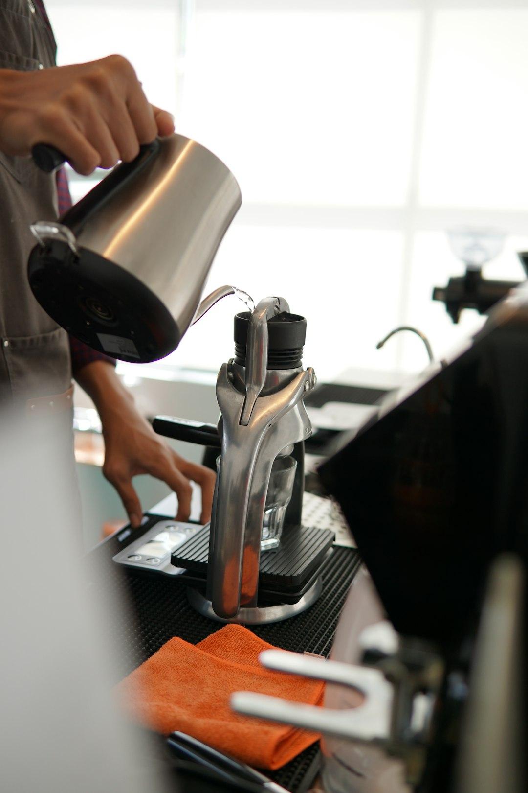 Barista wlewa gorącą wodę do ręcznego ekspresu Flair do espresso.