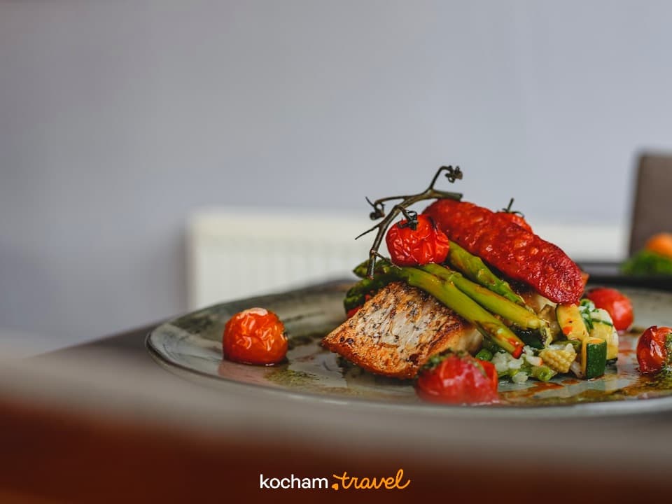 Grillowana ryba, szparagi, pomidory, czerwona kiełbasa, danie restauracyjne.