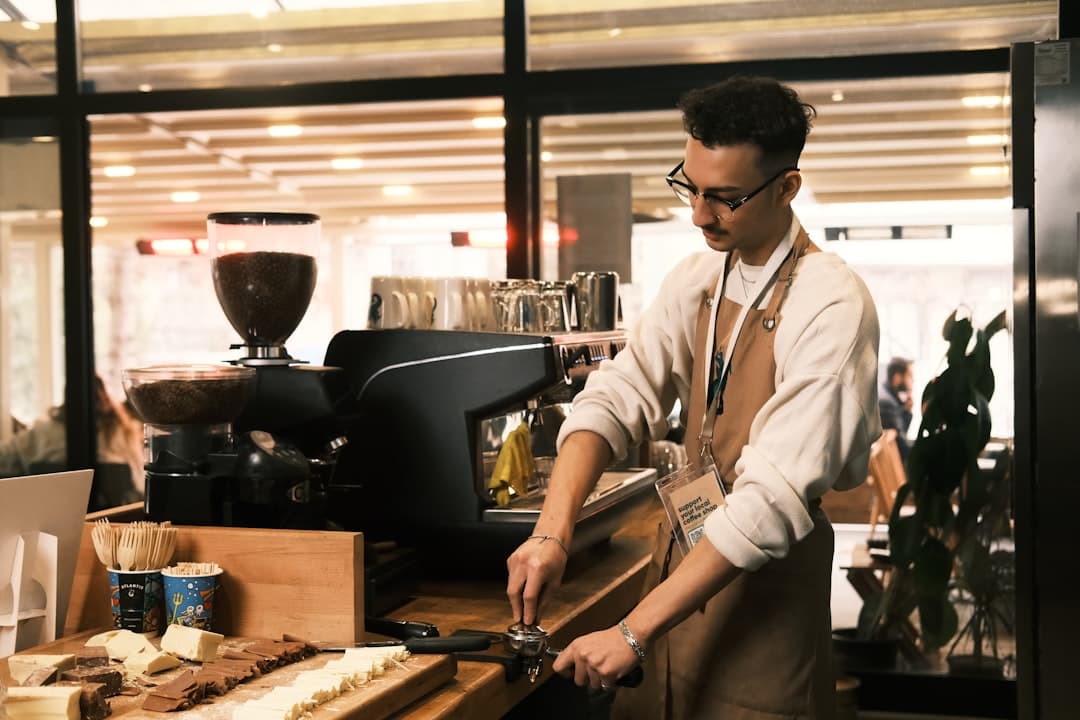 Barista przygotowuje kawę w kawiarni, ekspres do kawy, czekolada na blacie.
