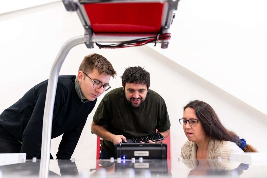 Trzy osoby współpracujące przy urządzeniu technologicznym w laboratorium.