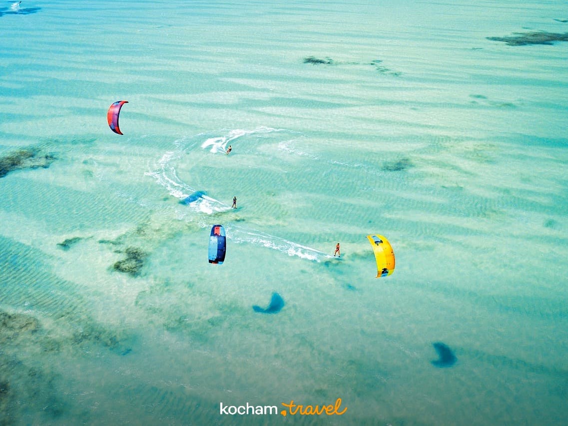 Kitesurferzy nad turkusową wodą, egzotyczne wakacje, sport wodny.