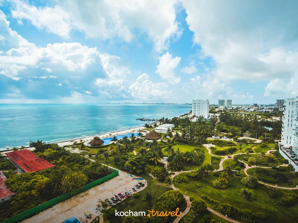 Panoramiczny widok na tropikalny kurort z plażą, turkusowym oceanem i hotelami.