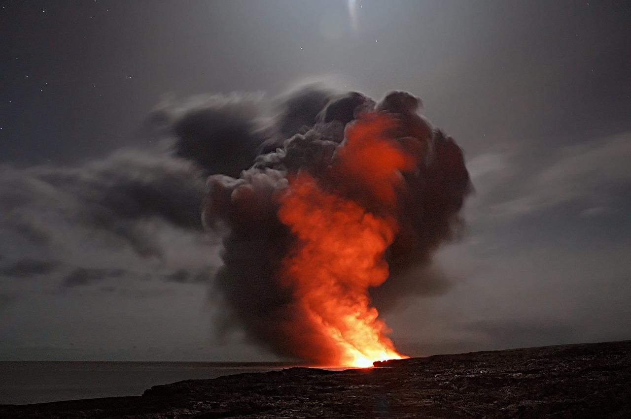 Nocna erupcja wulkanu z płonącą lawą i dymem nad oceanem.