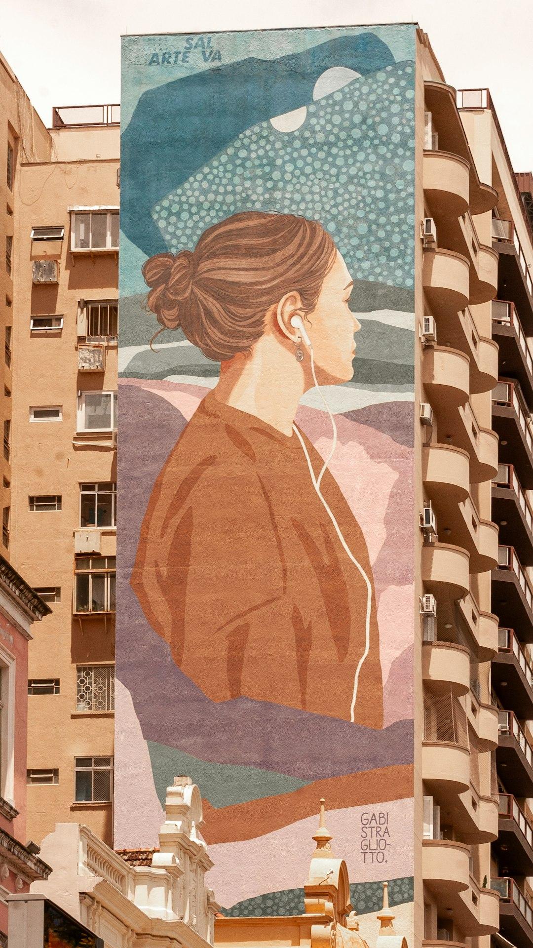 Mural Gabi Stragliotto: kobieta w słuchawkach na elewacji budynku.