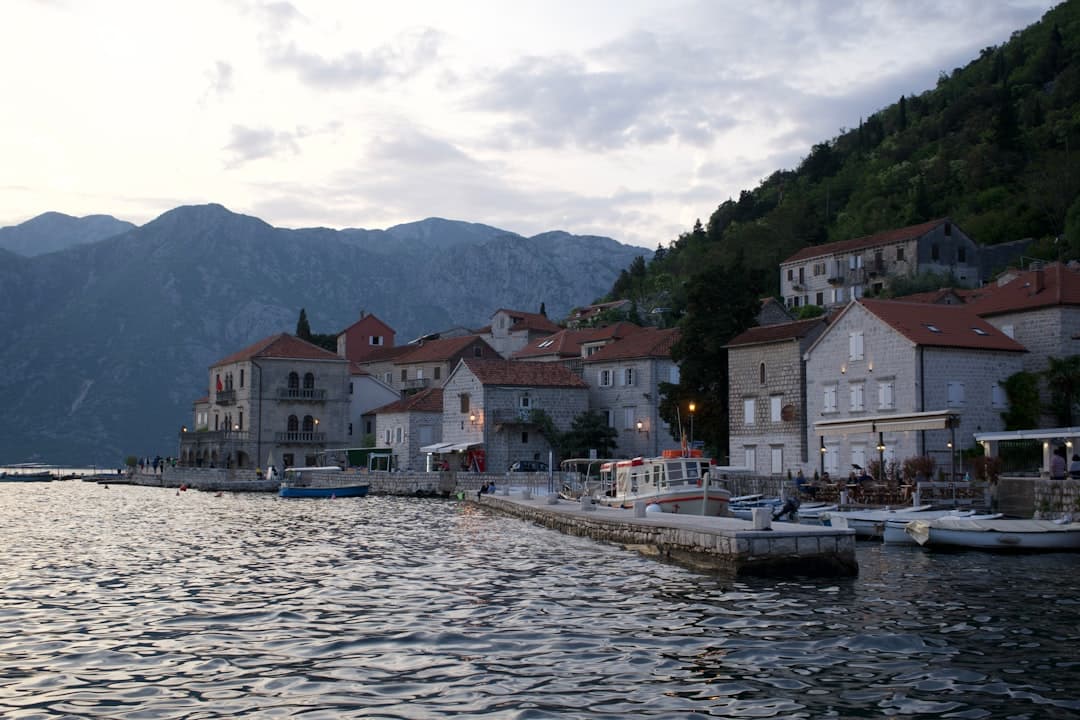 Nadmorskie miasteczko z kamiennymi domami, portem i łodziami w górskiej zatoce.