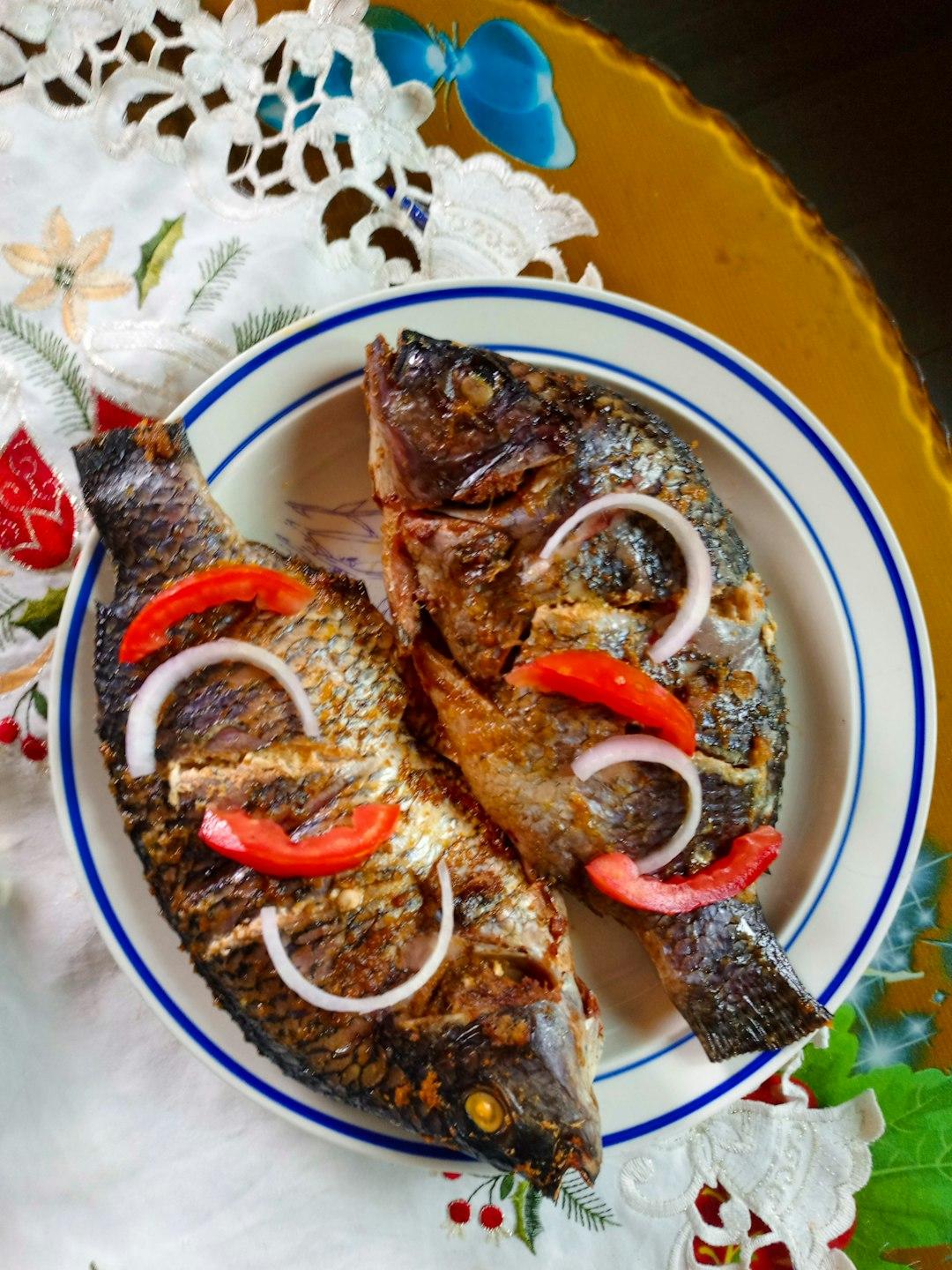 Smażone ryby tilapia z cebulą i pomidorami.