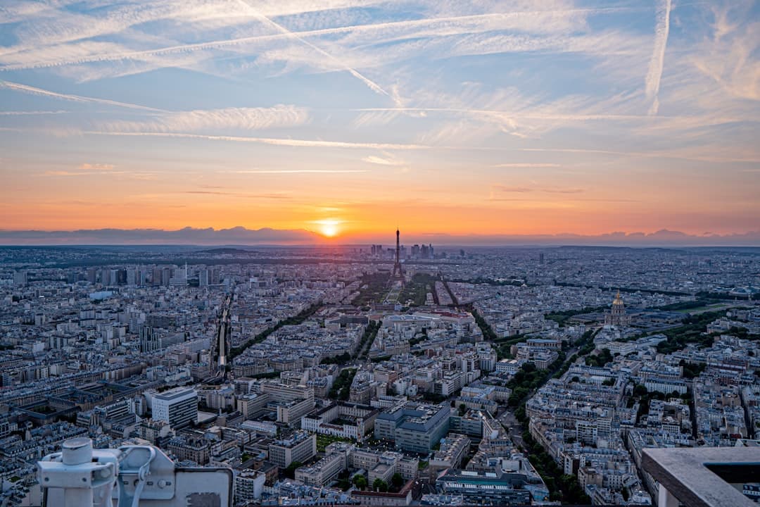 Panoramiczny widok Paryża o zachodzie słońca z Wieżą Eiffla na horyzoncie.