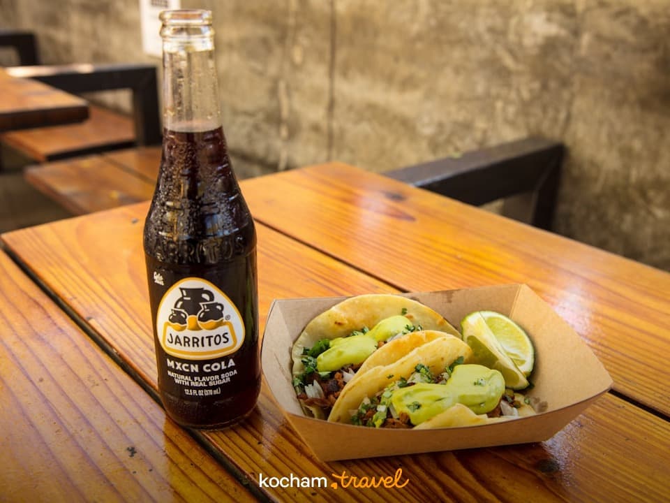Meksykańska cola Jarritos i tacos na drewnianym stole.