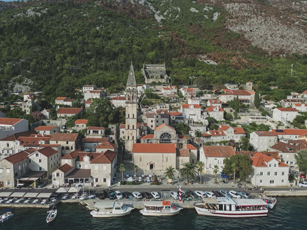 Widok Perastu, Czarnogóra: zabytkowe kamienice, dzwonnica, łodzie w zatoce.