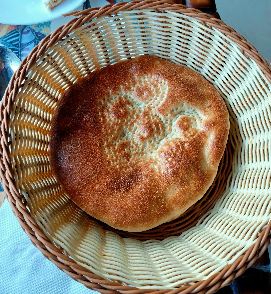 Okrągły chleb z wzorem w wiklinowym koszyku.