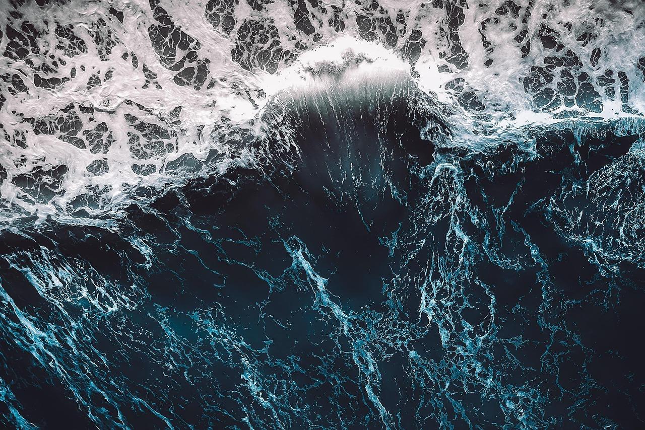 Potężna fala oceaniczna rozbijająca się, biała piana na wodzie.