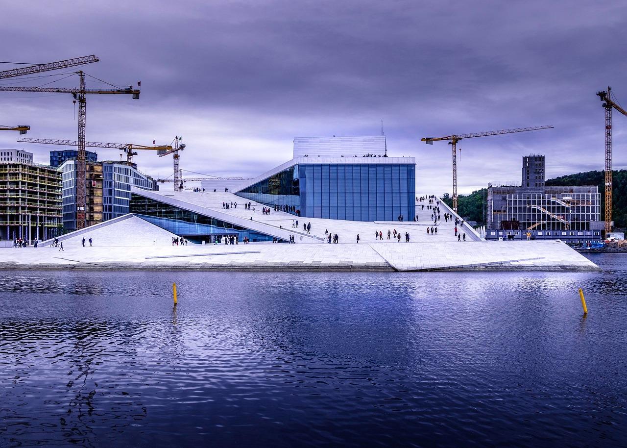 Nowoczesna Opera w Oslo, biała architektura, nabrzeże, żurawie budowlane.