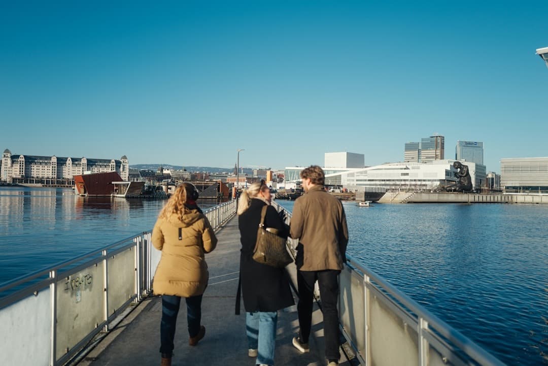 Ludzie spacerujący po nabrzeżu Oslo, widok na Operę i Muzeum Muncha.