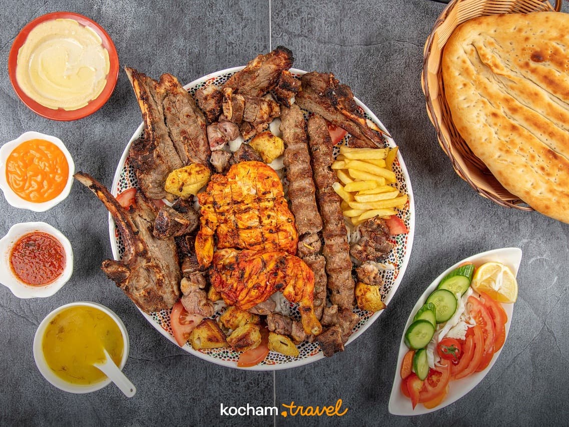 Obfite danie z grillowanym mięsem, kebabami, kurczakiem, chlebem i sosami.