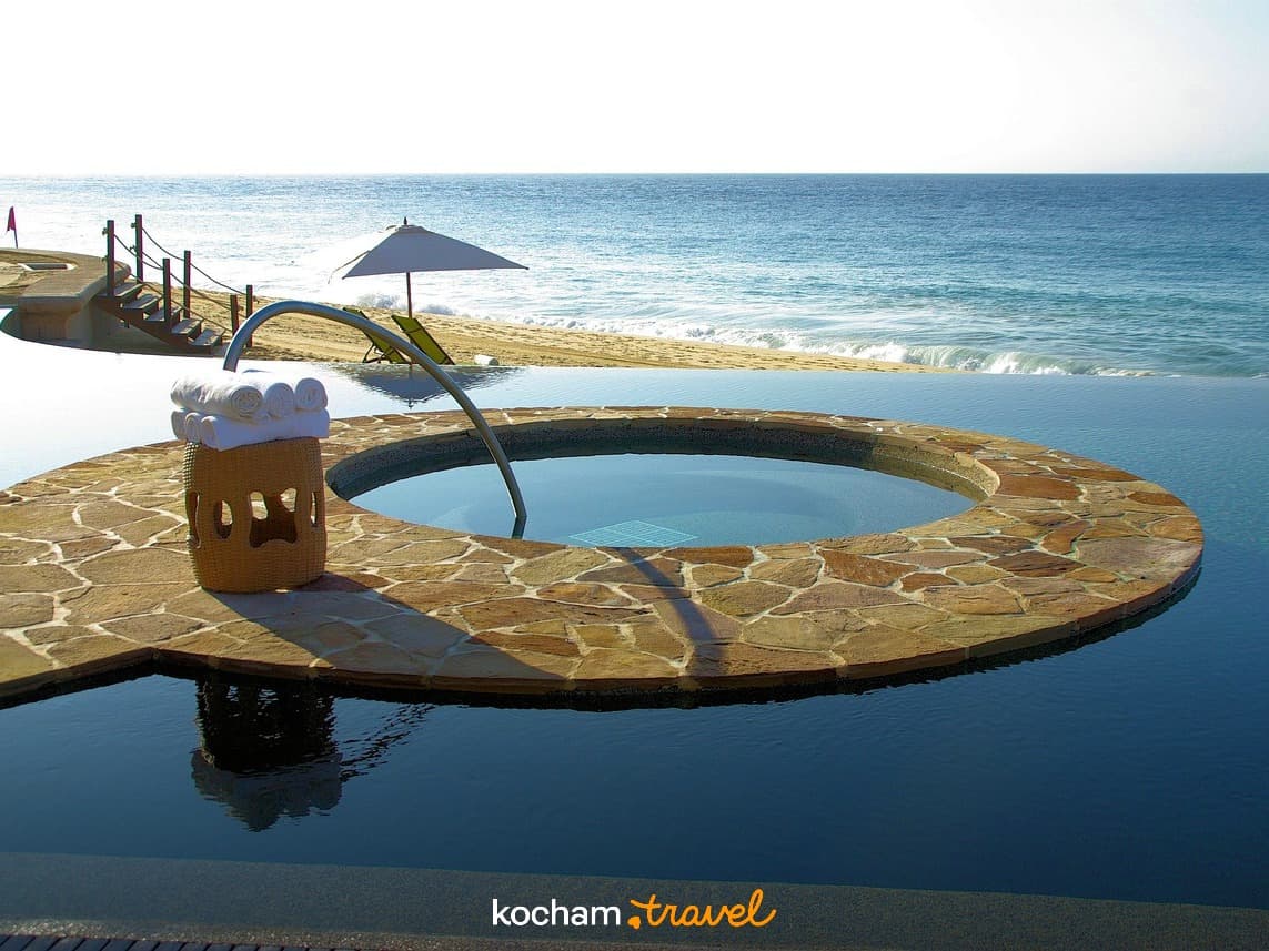 Luksusowy basen infinity z jacuzzi, piaszczysta plaża i ocean.
