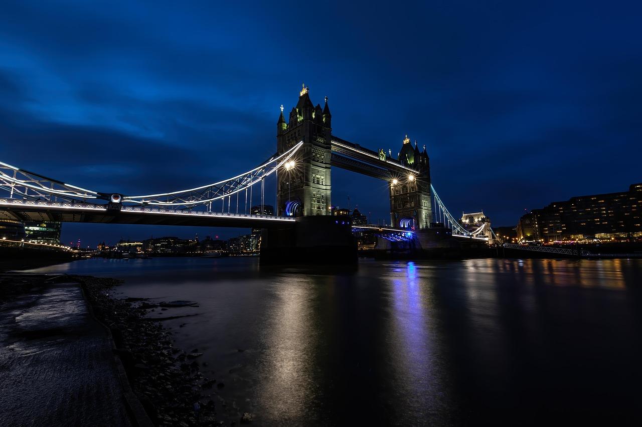Oświetlony Tower Bridge w Londynie nocą nad Tamizą.