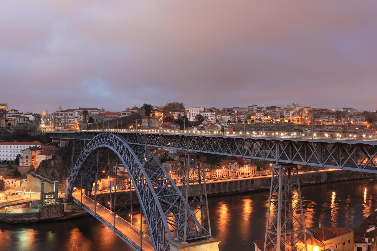 Oświetlony Most Dom Luís I nad rzeką Douro w Porto wieczorem.