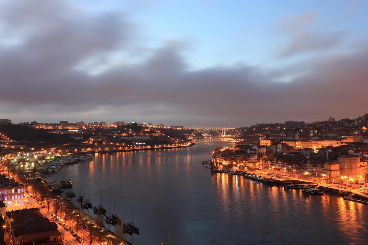 Rozświetlone Porto nocą, rzeka Douro, most Dom Luís I i zabytkowe nabrzeża.