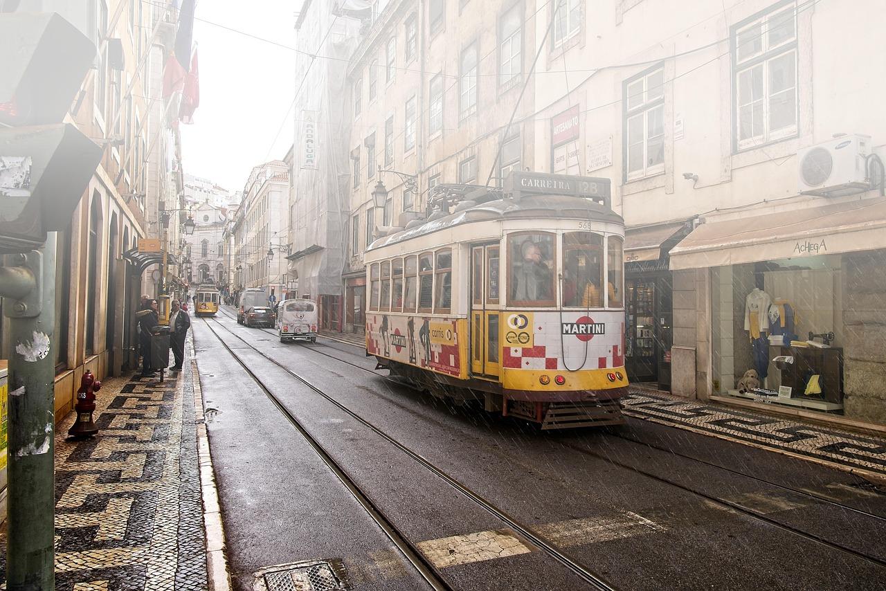 Ikoniczny tramwaj Lizbony na mokrej, brukowanej ulicy miasta.
