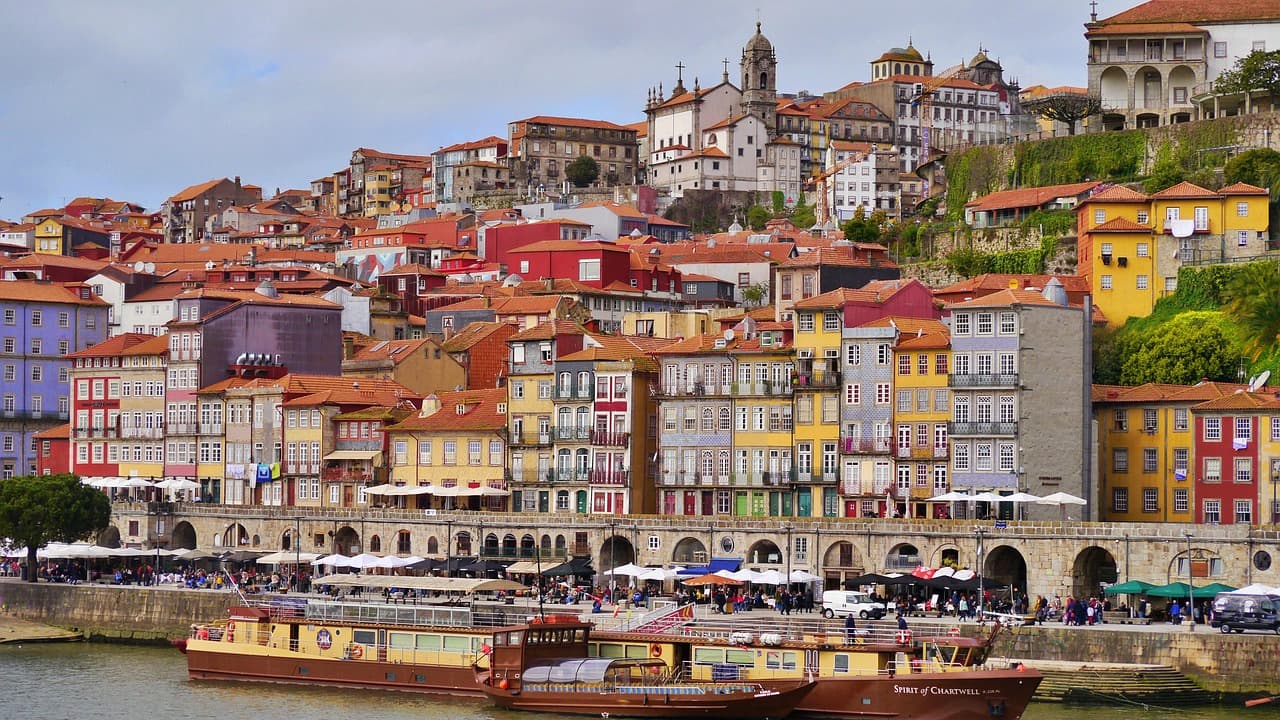 Historyczne, kolorowe kamienice Porto nad rzeką Douro i łodzie turystyczne.