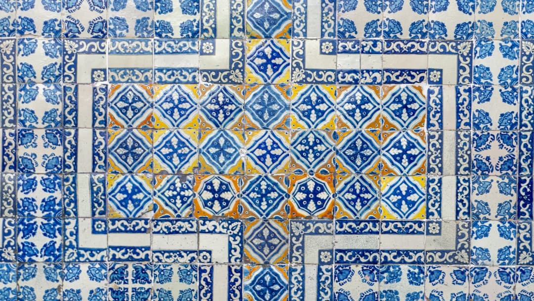 Tradycyjne niebiesko-białe płytki azulejo z żółtym wzorem na ścianie.