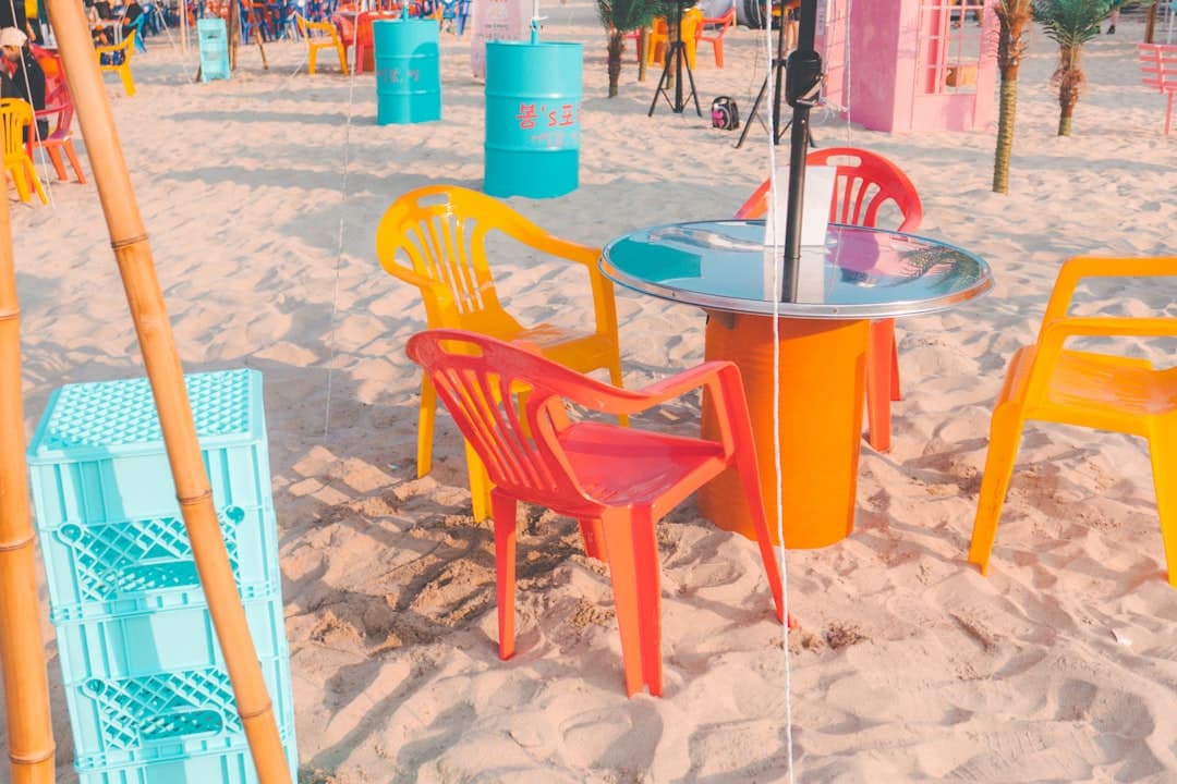 Kolorowe krzesła i stoliki na plaży z piaskiem.