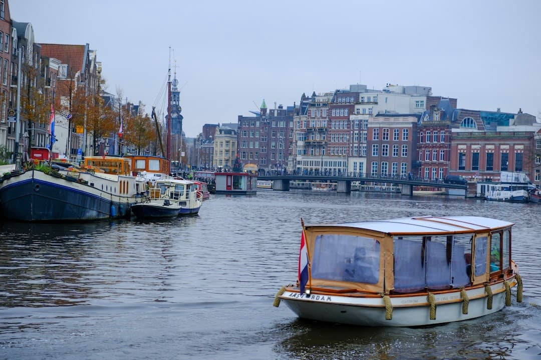 Kanał w Amsterdamie, rejs łodzią, zabytkowe kamienice, pochmurny dzień.