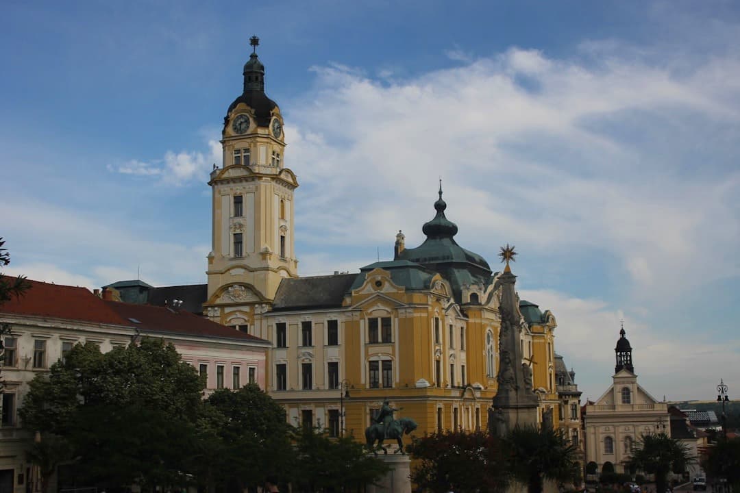 Historyczny plac: wieża zegarowa, barokowy budynek, pomnik konny, kolumna