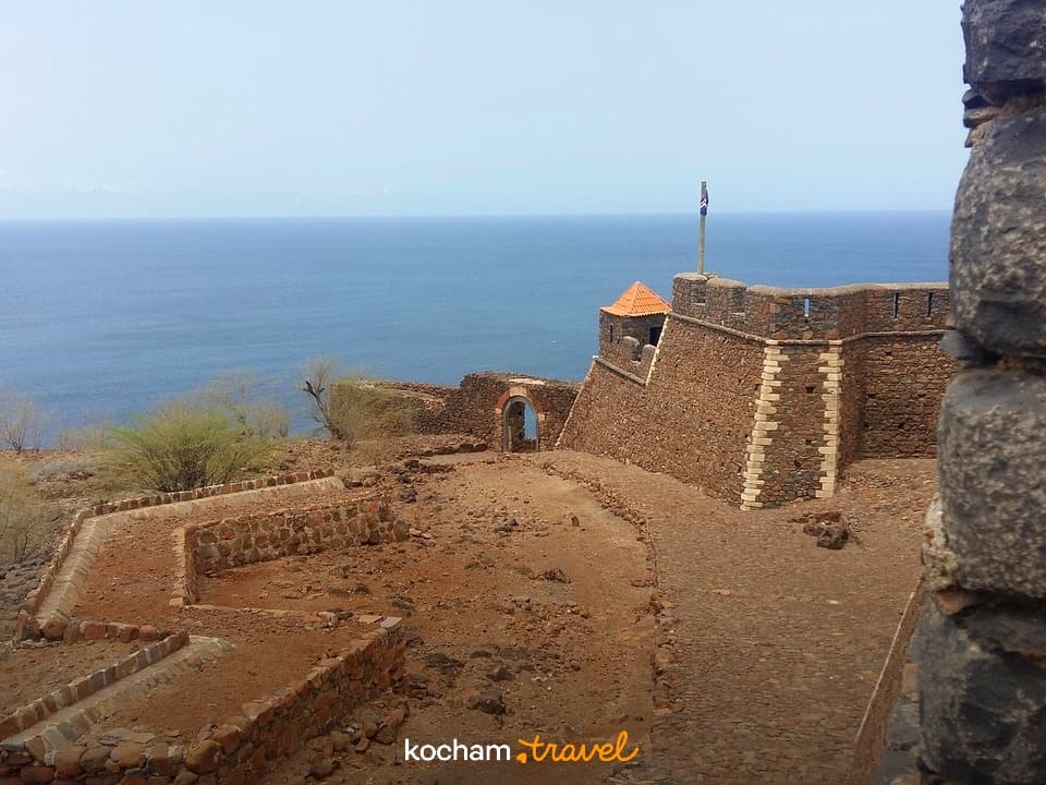 Zabytkowa kamienna twierdza na klifie z widokiem na ocean.