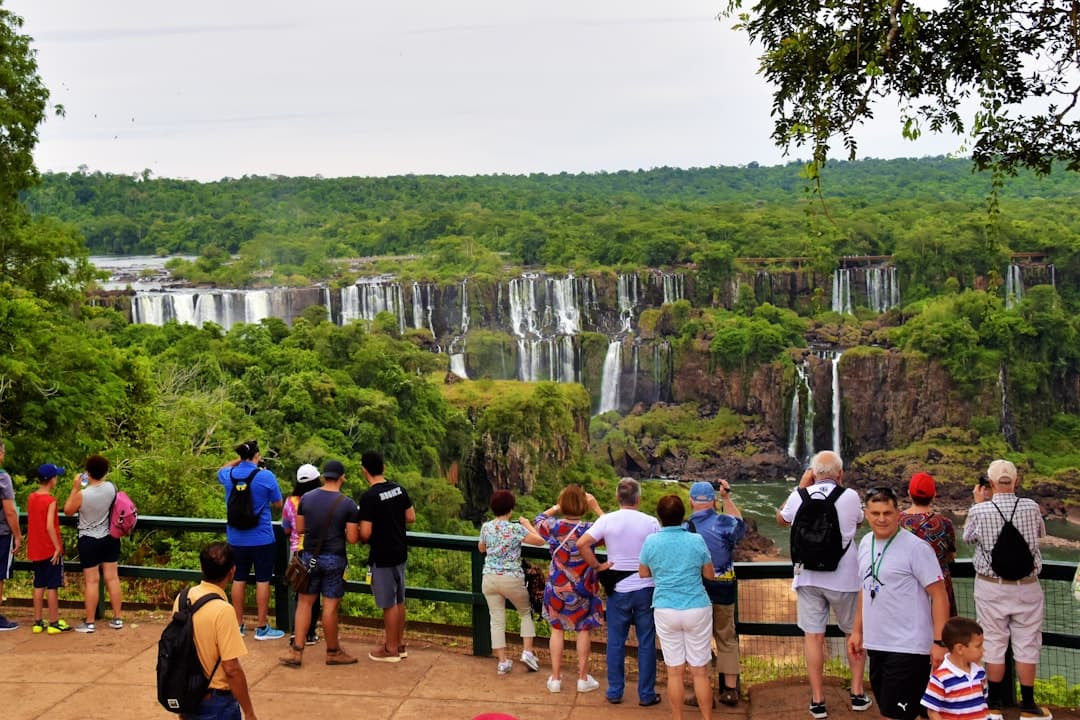 Turyści podziwiają rozległe wodospady Iguazu w zielonej dżungli.