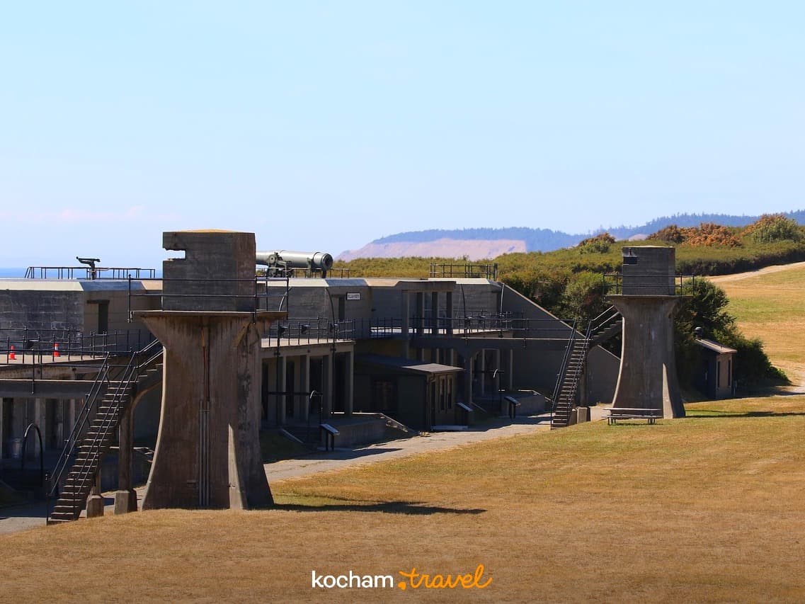 Historyczne betonowe bunkry wojskowe z armatami i widokiem na ocean.