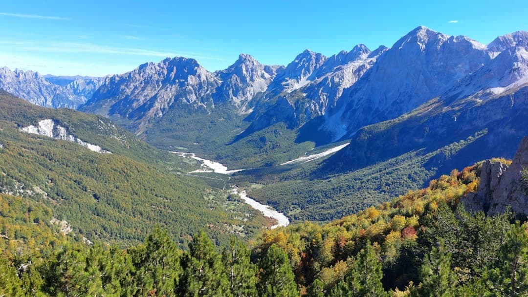 Górska dolina, rzeka, zielone lasy, jesienne kolory, panoramiczny widok.