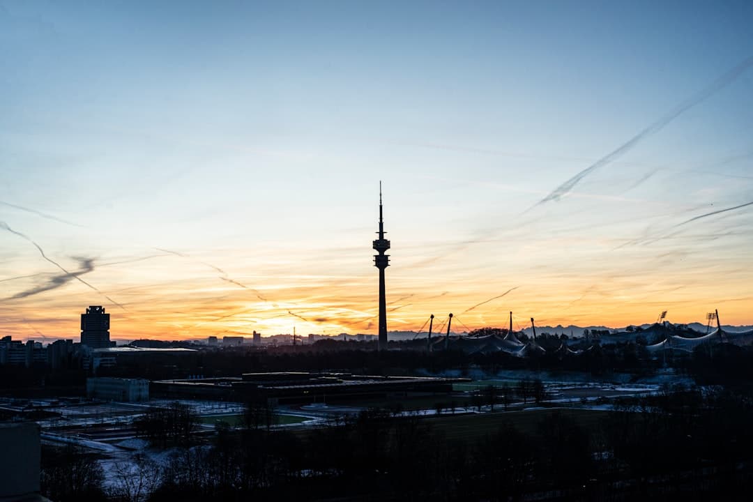 Panorama Monachium z wieżą olimpijską i parkiem o zachodzie słońca.
