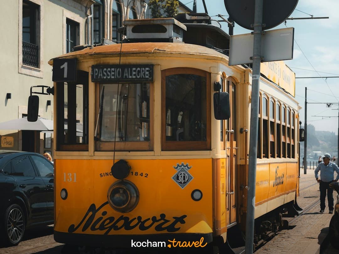 Żółty zabytkowy tramwaj na brukowanej ulicy w Porto, Portugalia.