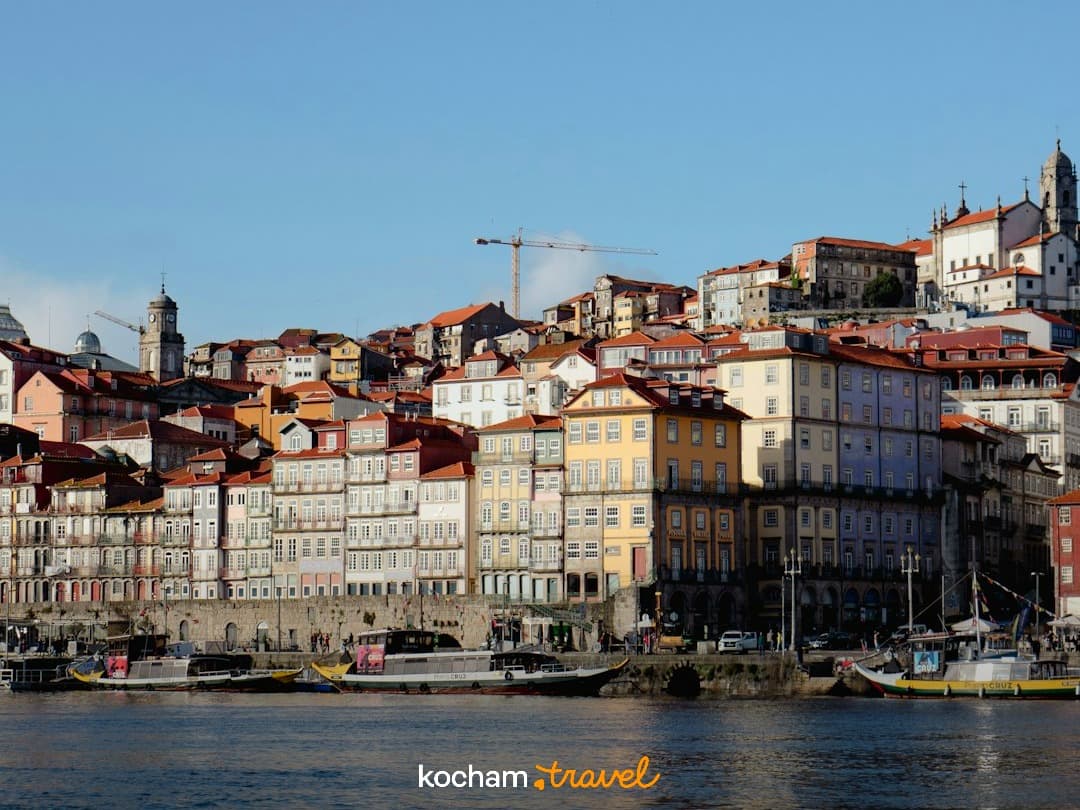Kolorowe historyczne budynki Porto nad rzeką Douro z łodziami.