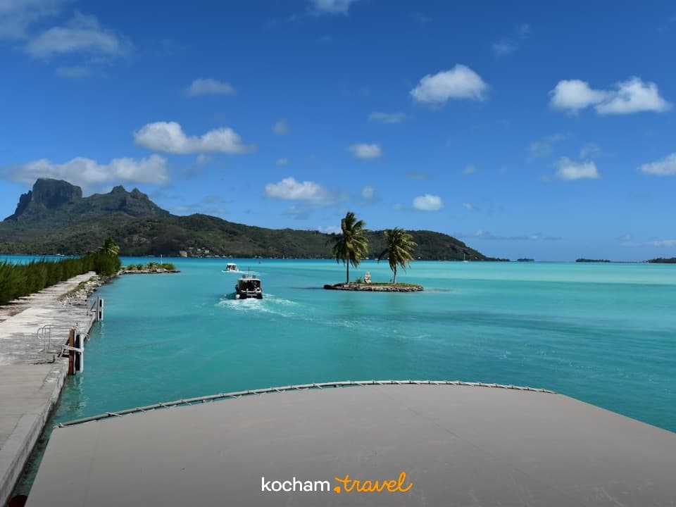 Bora Bora, turkusowa laguna, palmy, góry, łodzie, tropikalny raj.