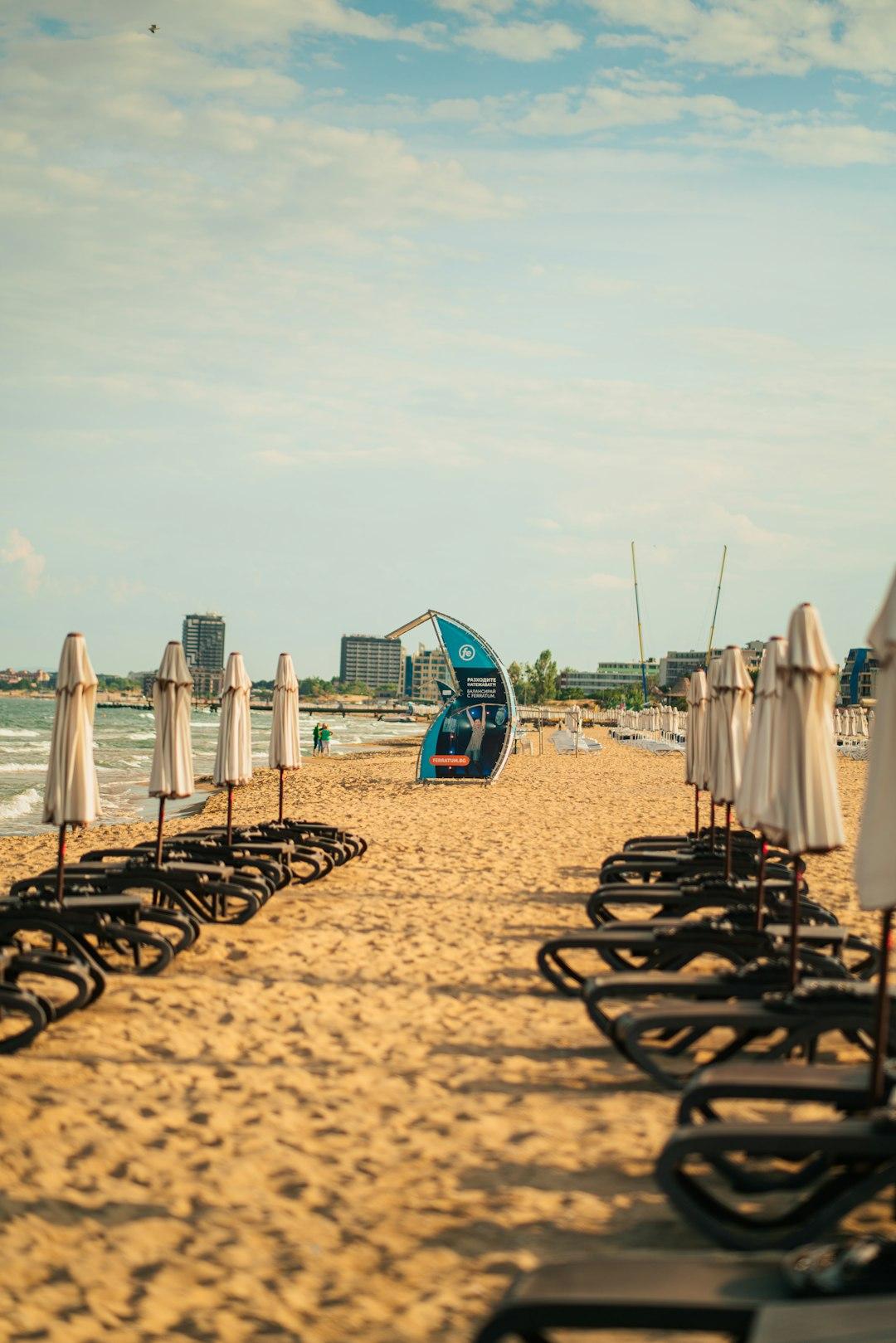 Piaszczysta plaża z leżakami i parasolami.