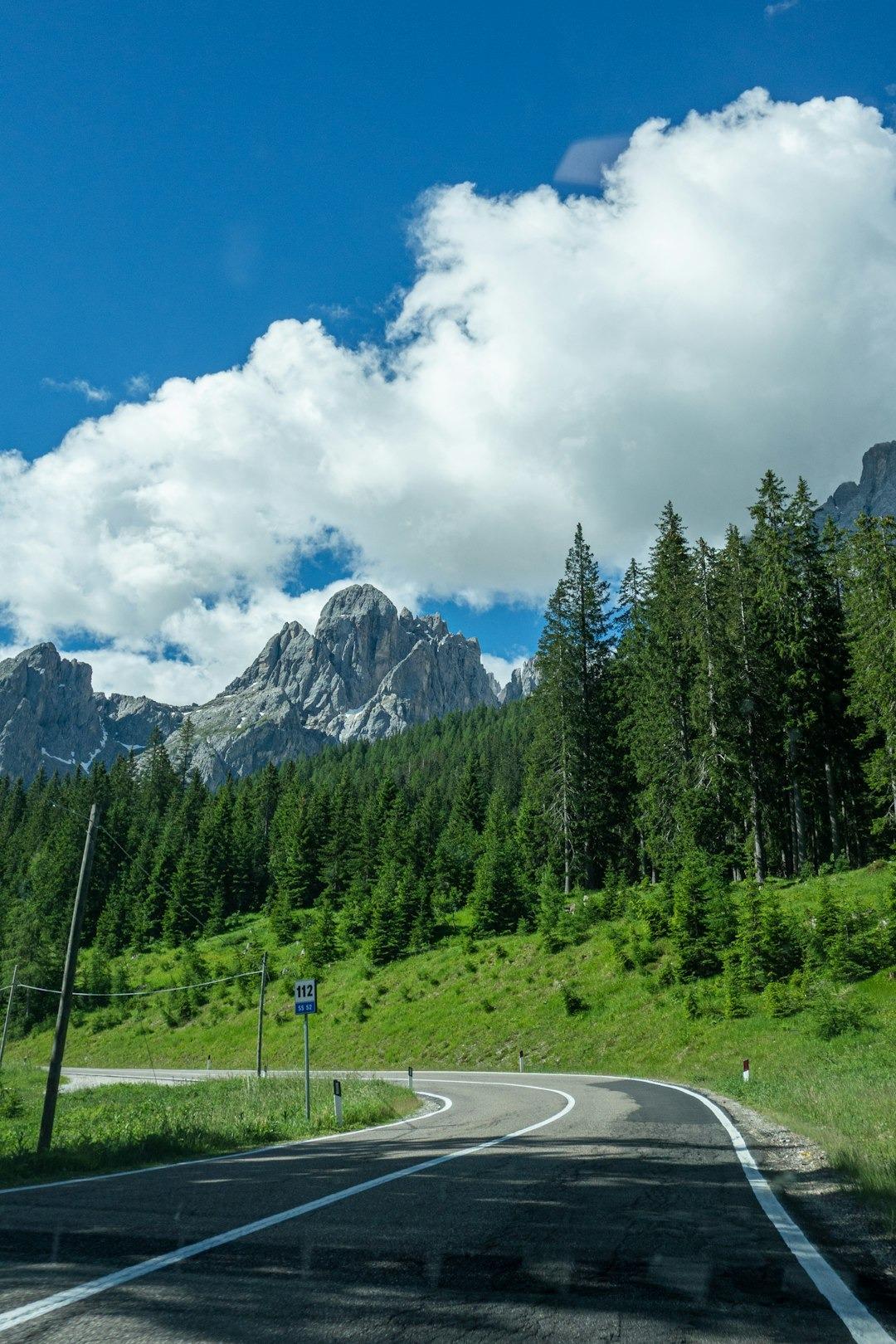 Kręta droga górska, las, szczyty Dolomitów, słoneczny dzień.