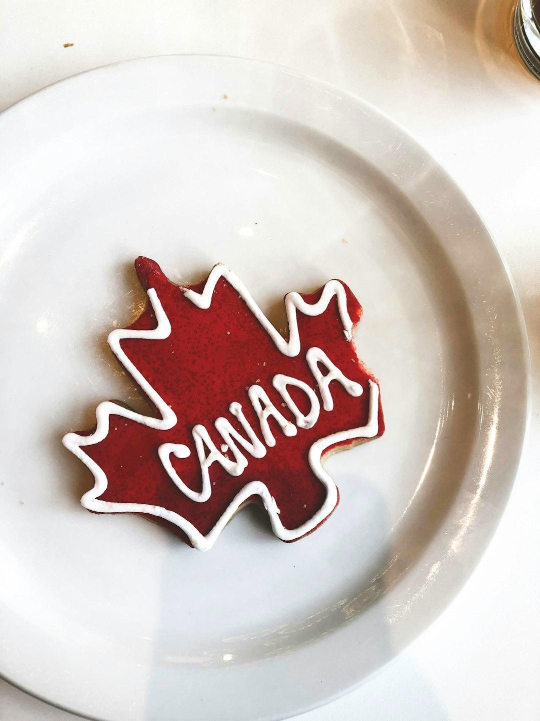 Ciasteczko w kształcie liścia klonu z napisem "CANADA" na talerzu.