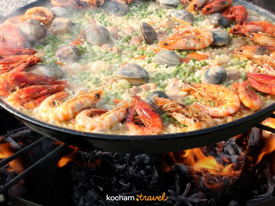 Paella z krewetkami, małżami, ryżem gotowana na otwartym ogniu.