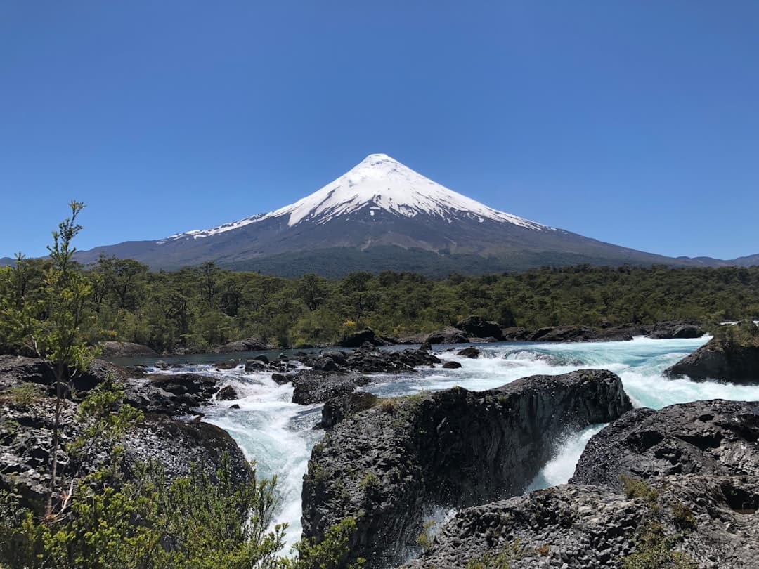 Ośnieżony wulkan Osorno, turkusowe bystrza rzeki Petrohué, skalisty krajobraz Chile.