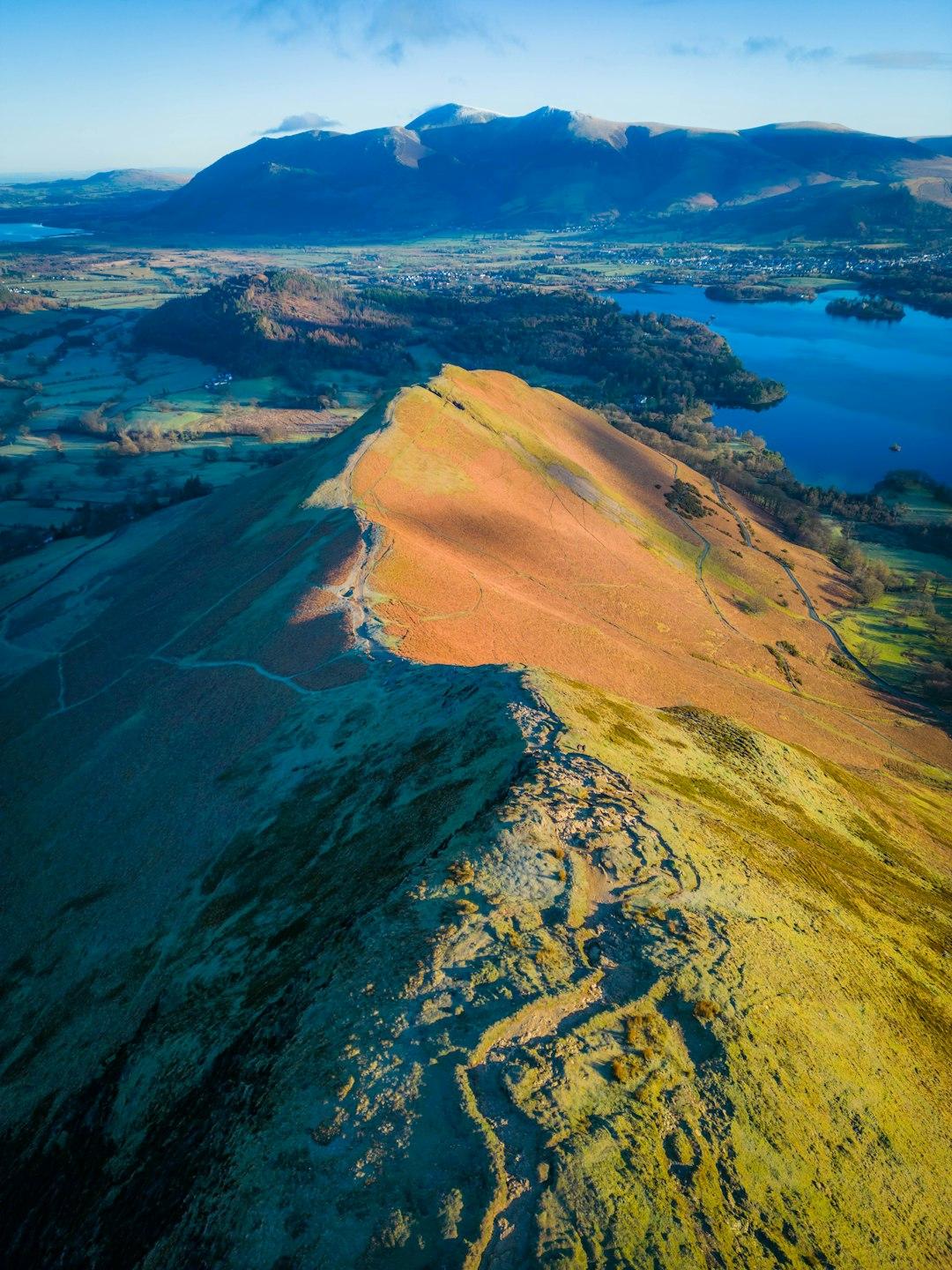 Górski grzbiet, jezioro Derwentwater i ośnieżone szczyty w Krainie Jezior.