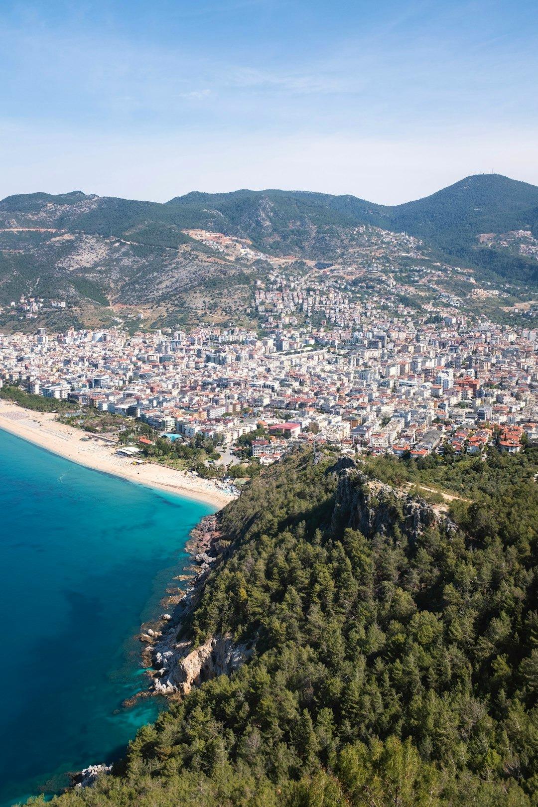 Panoramiczny widok na miasto Alanya, plażę, turkusowe morze i góry.