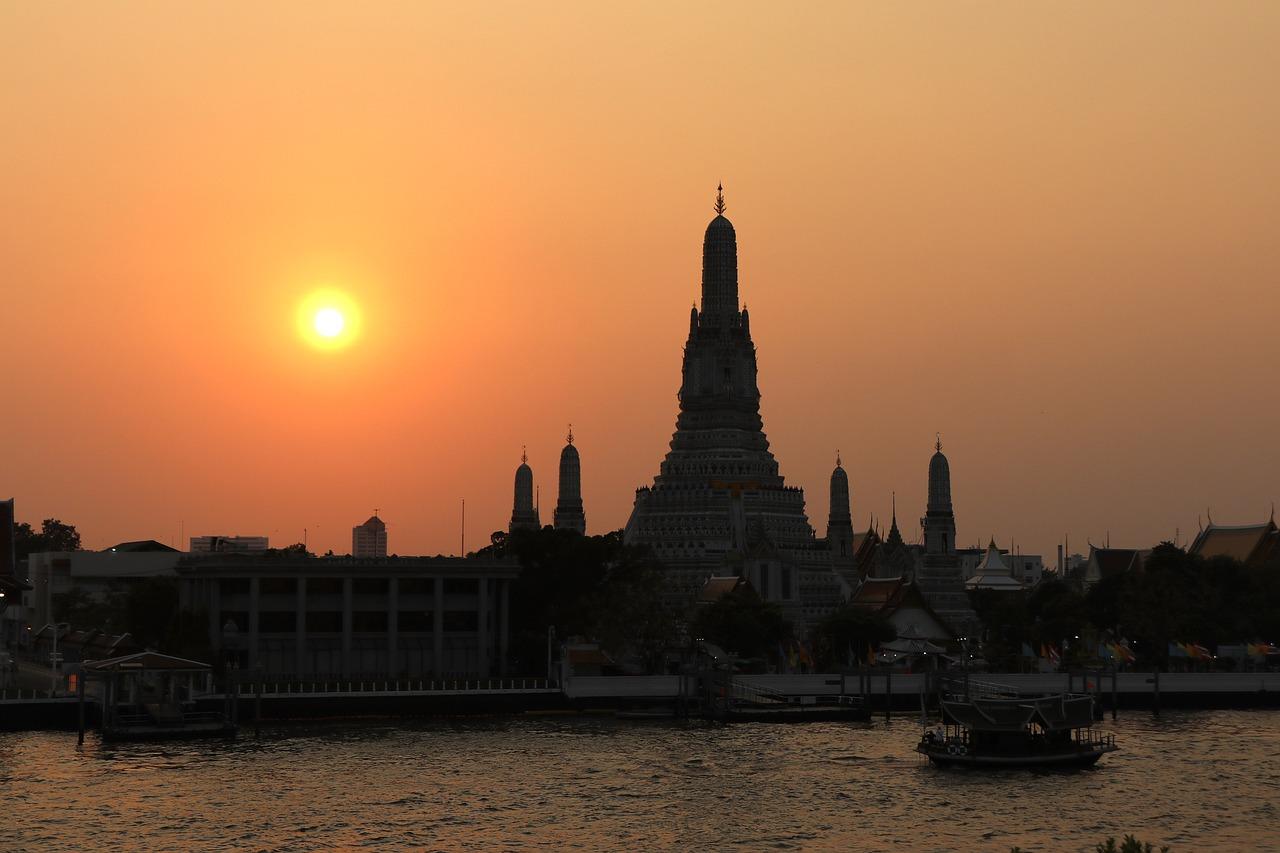 Sylwetka świątyni Wat Arun o zachodzie słońca nad rzeką Chao Phraya.