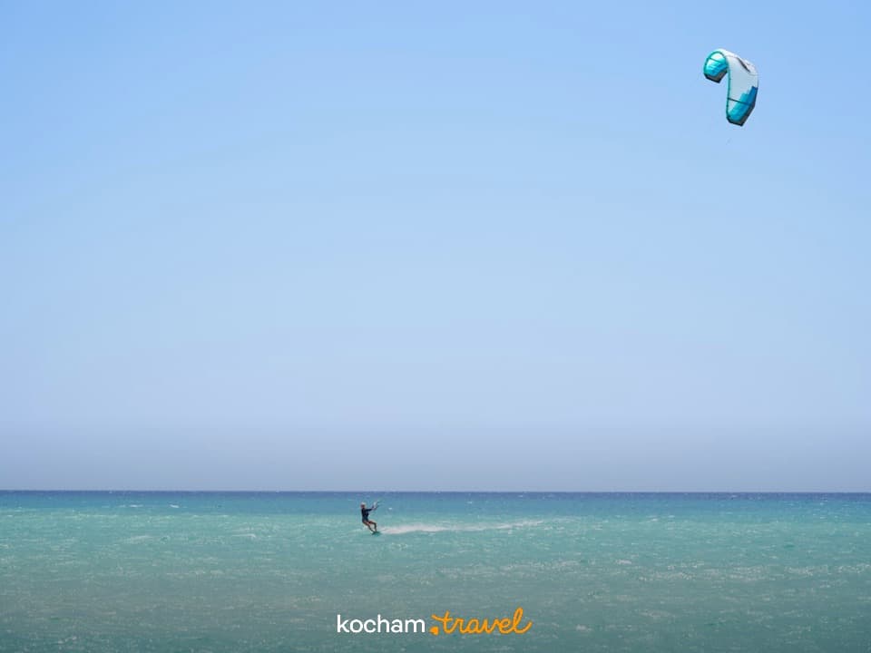 Kitesurfer na turkusowym morzu pod błękitnym niebem.