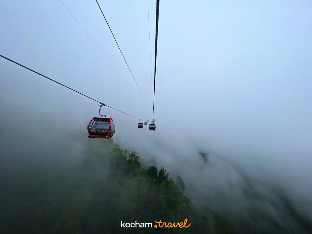 Kolejka linowa Baden Mountain, czerwone gondole ponad mglistą górą.