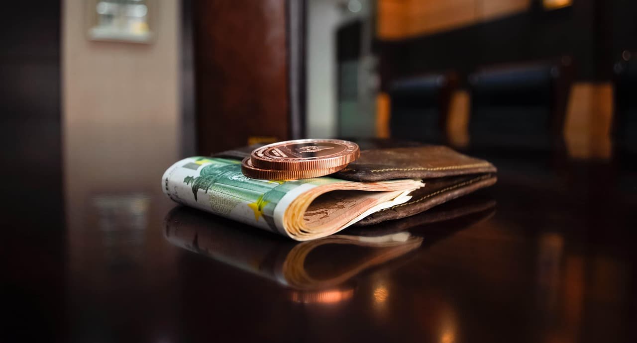 Portfel z banknotami euro i dwoma monetami kryptowalutowymi.