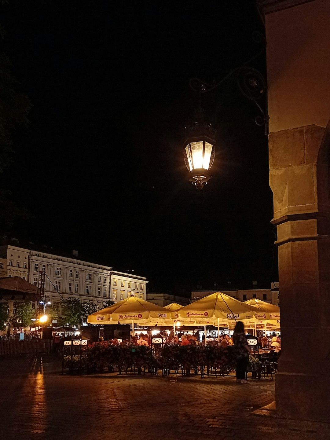 Tętniąca życiem nocna restauracja z żółtymi parasolami na rynku.